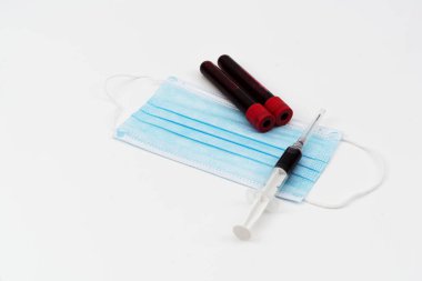 Şırınga, kan tüpü ve yüz maskesi beyaz arka planda izole edilmiş ve seçici odaklanma