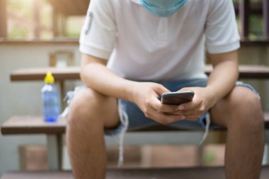 Evde gözaltı, Coronavirus salgını, elinde akıllı telefon tutan adam, akıllı telefona odaklan..