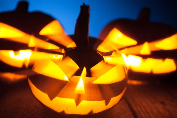 Três abóboras jack-o-lanterna brilhando no escuro — Fotografia de Stock