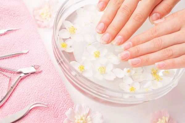 Mooie dames handen met manicure in kom met water — Stockfoto