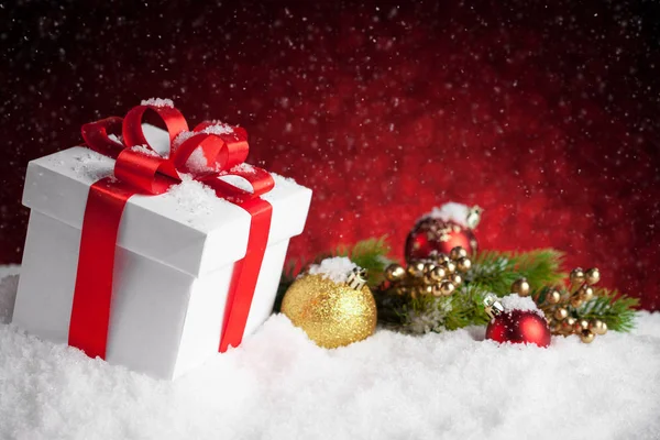 Kerstcadeau en kerstballen op rode bokeh achtergrond — Stockfoto