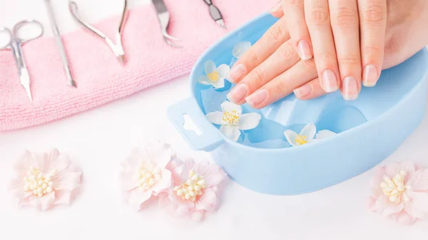 Mooie dames handen met manicure in kom met water — Stockfoto