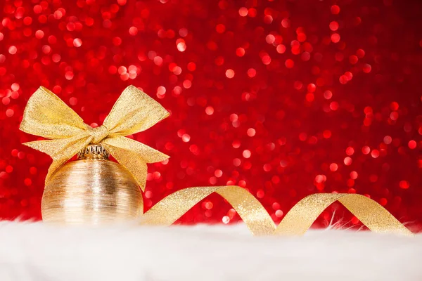 Kerst gouden bal en strik op de glanzende achtergrond rood glitter — Stockfoto