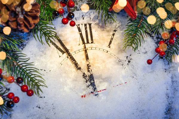 Weihnachtsuhr und Tannenzweige mit Schnee bedeckt — Stockfoto