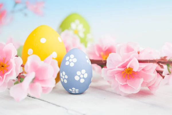 Frühlingsblumen und bunte Ostereier auf blauem Grund — Stockfoto