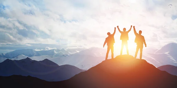 Silhouette of the team on the peak of mountain — Stock Photo, Image