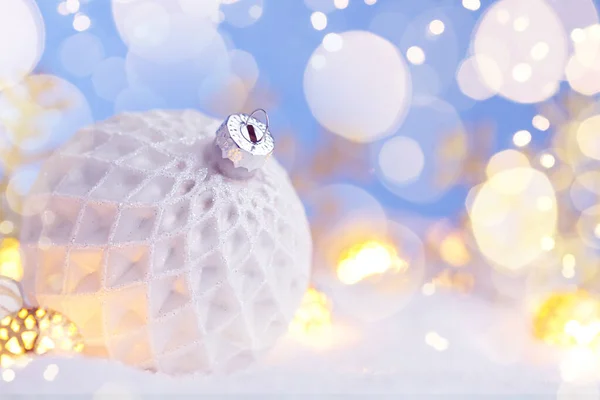 Bola branca de Natal com flocos de neve na neve . — Fotografia de Stock