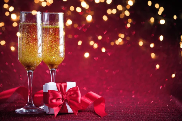 Két pohár pezsgő ajándék piros háttér — Stock Fotó