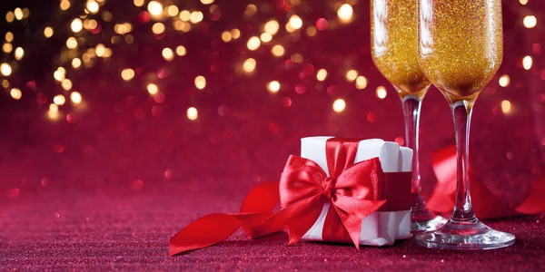 Two glasses of champagne with gift on red background — Stock Photo, Image