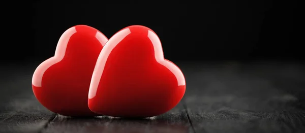 Dwa czerwone serca na drewnianym stole na ciemnym tle — Zdjęcie stockowe