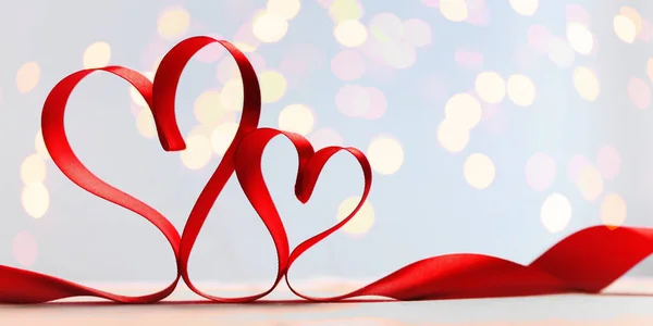 Two red ribbon hearts on blue background with gold lights. — Stock Photo, Image