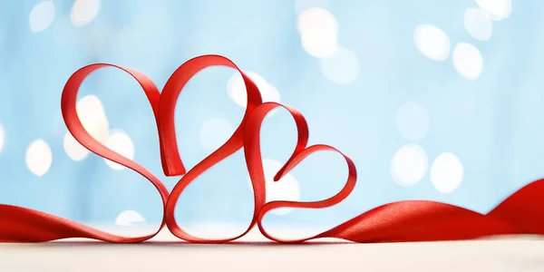 Ribbon shaped as hearts on blue background with lights. — Stock Photo, Image