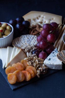 peynir, üzüm, kraker ve siyah bir zemin üzerine zeytin