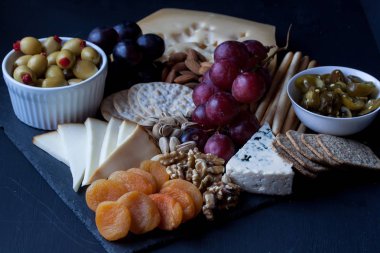 peynir, üzüm, kraker ve siyah bir zemin üzerine zeytin