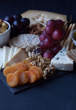 peynir, üzüm, kraker ve siyah bir zemin üzerine zeytin