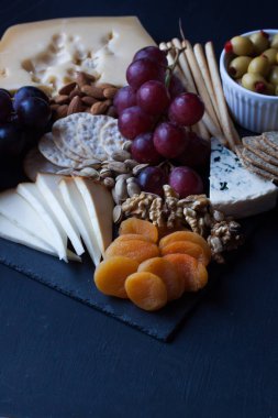 peynir, üzüm, kraker ve siyah bir zemin üzerine zeytin
