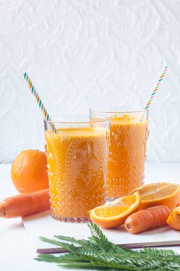 beyaz zemin üzerine portakal ve havuç suyu
