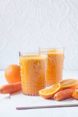 beyaz zemin üzerine portakal ve havuç suyu