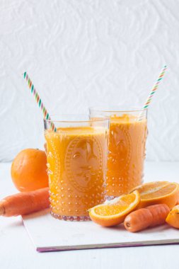 beyaz zemin üzerine portakal ve havuç suyu