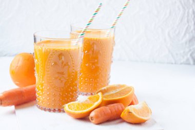 beyaz zemin üzerine portakal ve havuç suyu