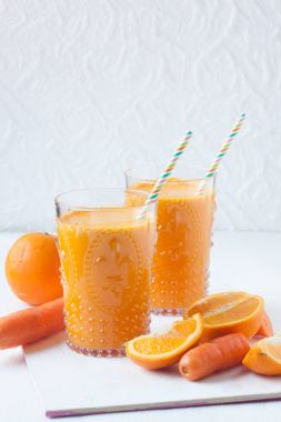 beyaz zemin üzerine portakal ve havuç suyu