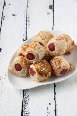  Sosis bir tabak içinde ahşap beyaz bir arka plan üzerinde rulo.