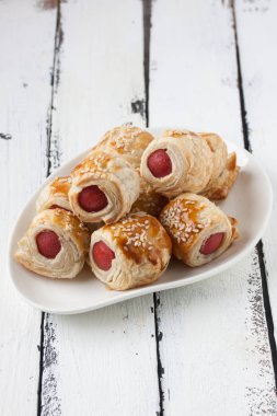  Sosis bir tabak içinde ahşap beyaz bir arka plan üzerinde rulo.