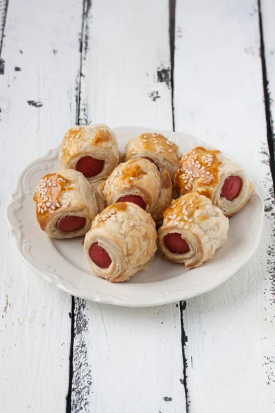 Sausage rolls in a plate on a wooden white background — Stock Photo, Image