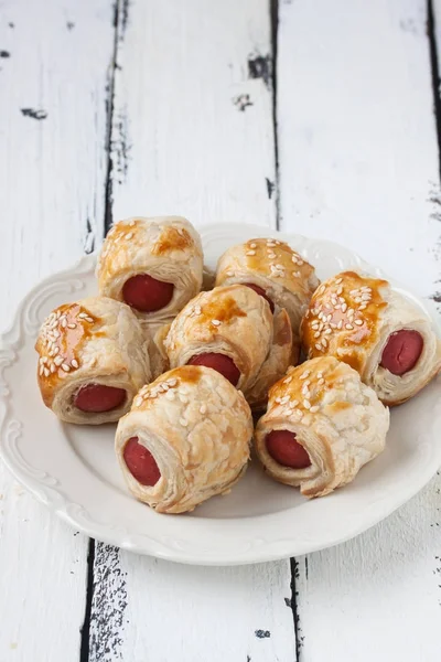 Sausage rolls in a plate on a wooden white background — Stock Photo, Image