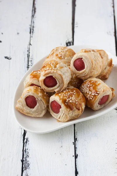 Sausage rolls in a plate on a wooden white background — Stock Photo, Image