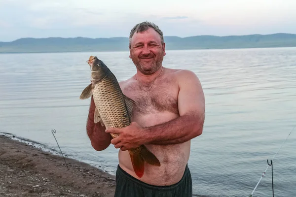 Un uomo robusto con una carpa grossa. Khakassia, Russia — Foto Stock