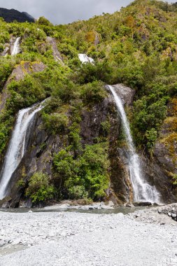 Franz Josef Buzulu yolunda küçük bir çift şelale. Yeni Zelanda