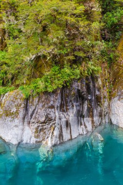 Mavi suyun üzerindeki sarp kayalıklar. Güney Adası, Yeni Zelanda