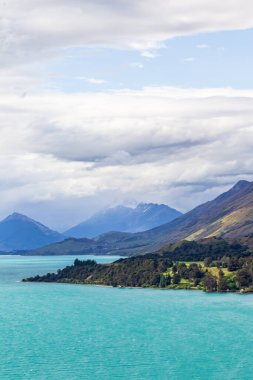 Picturesque shores of Lake Wakatipu. Green capes and snow-capped mountains. South Island, New Zealand clipart