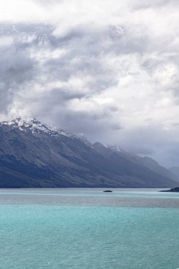 Kar kaplı dağın üzerine yağmur bulutları. Wakatipu Gölü. Yeni Zelanda