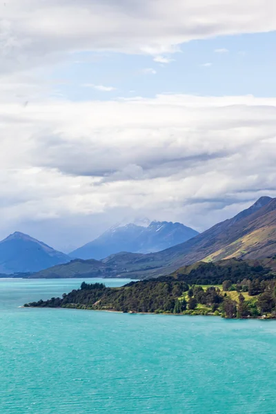 Wakatipu Gölü 'nün resimli kıyıları. Yeşil pelerinler ve karlı dağlar. Güney Adası, Yeni Zelanda