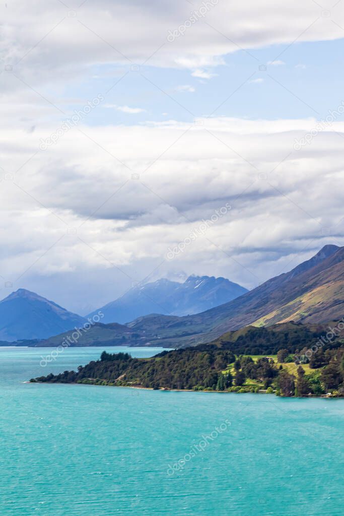 Picturesque shores of Lake Wakatipu. Green capes and snow-capped mountains. South Island, New Zealand