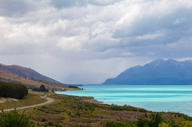 Güney Alplerine giden yol. Turkuaz gölü kıyısında, Pukaki. Güney Adası, Yeni Zelanda