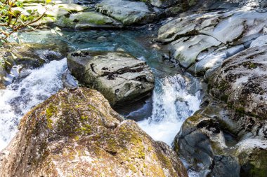 Bir akarsu bacanın içinde kayboluyor. Yeni Zelanda 'da huni yarığı. Taşların arasında akarsu. Güney Adası