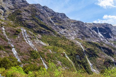 Fiordland yolundaki sarp kayalıklardan gelen küçük şelaleler ve akarsular. Güney Adası, Yeni Zelanda