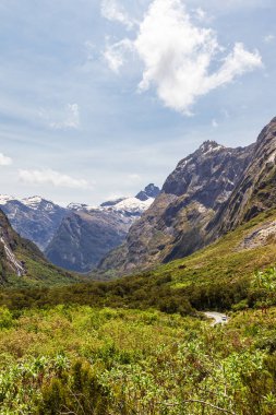 Yeşil bir vadi ve Fiordland yolunda karla kaplı dağ tepeleri. Güney Adası, Yeni Zelanda
