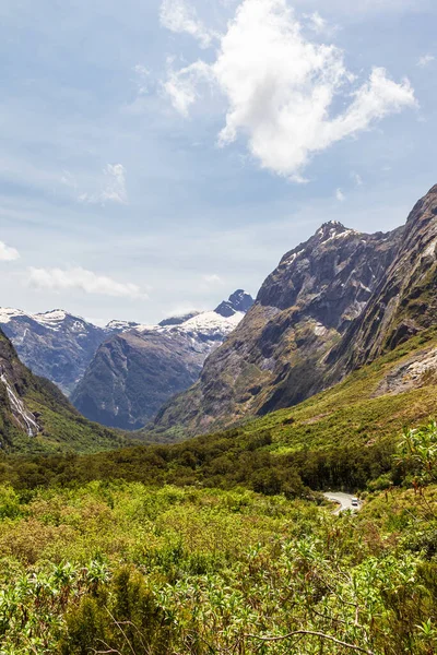 Yeşil bir vadi ve Fiordland yolunda karla kaplı dağ tepeleri. Güney Adası, Yeni Zelanda