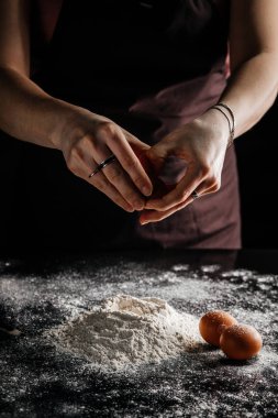 Una bir yumurta düşer, eller kabuğu tutar, pişirir, eller yumurtayı tutar.