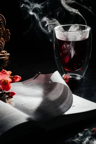 book, spring flowers on a dark background, smoke, hot tea