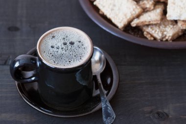 Ahşap bir masada bir fincan kahve ve bisküvi ile bir yemek var