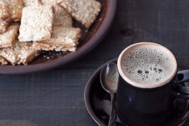 Ahşap bir masada bir fincan kahve ve bisküvi ile bir yemek var