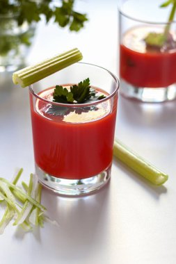 Bir bardak domates suyu ve maydanoz süslemesi, domates suyu ve kereviz filizi ile ikinci bir bardak..