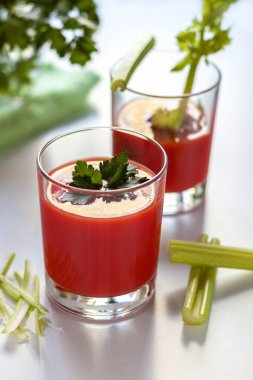 Bir bardak domates suyu ve maydanoz süslemesi, domates suyu ve kereviz filizi ile ikinci bir bardak..