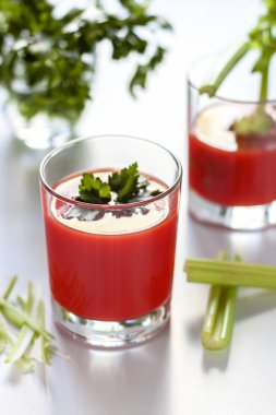 Bir bardak domates suyu ve maydanoz süslemesi, domates suyu ve kereviz filizi ile ikinci bir bardak..