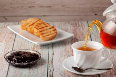 Çaydanlıkta taze çay, masada da kurabiye ve reçel.